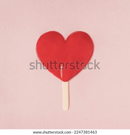 Red paint in the shape of a heart with a silhouette of melted ice cream on a stick. Minimal valentine or love concept. Flat lay.