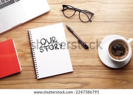 Our Story, motivational words and sentences for work and life. Quote sentence in notebook with laptop, pen, coffee over wooden background. Royalty-Free Stock Photo #2247386795