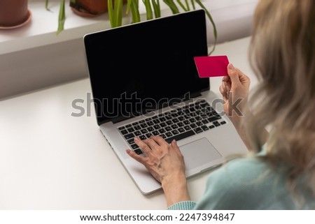 Young woman holding credit card and using laptop computer. Businesswoman or entrepreneur working at home. Online shopping, e-commerce, internet banking, spending money, working from home concept.