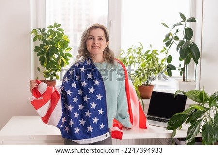 Picture of happy young lady with USA flag using laptop computer. Looking camera.