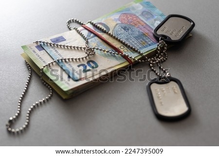 The soldier's military tokens are on dollar bills. Concept: cost of living soldier, military pensions, soldiers of fortune and mercenary Royalty-Free Stock Photo #2247395009