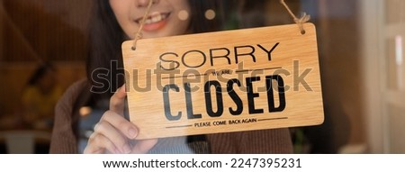 Pretty asian young owner retail, coffee shop woman turning sign board to closed after finished work, job and protection to pandemic of coronavirus. Close store due to lockdown, quarantine of covid. Royalty-Free Stock Photo #2247395231