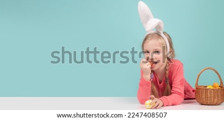 Easter child. Funny girl wearing bunny ears and having fun with Easter eggs. Cute little child girl wearing bunny ears on Easter day. Panoramic web banner frame.