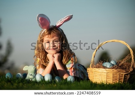 Easter egg hunt in garden. Child boy playing in field, hunting easter eggs, on sky background with copy space. Closeup portrait of cute kids.