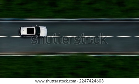 Panning shot of car driving on the road taken from above Royalty-Free Stock Photo #2247424603