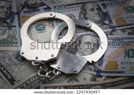 metal handcuffs against the background of the cash currency American dollars. The concept of bribery or criminal money. Royalty-Free Stock Photo #2247430497