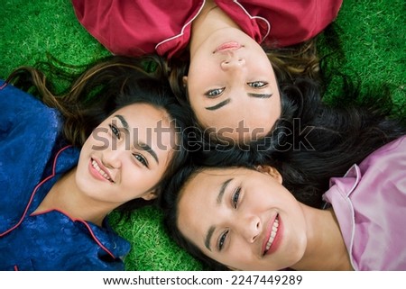 Funny pretty Asian girls wear sleepwear having fun look at camera relax on grass