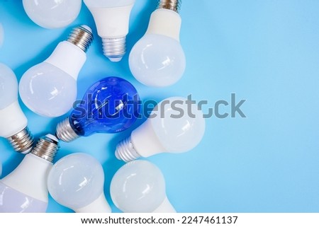 Top view of pile of white and blue light bulb on light blue background , unique and differentiation concept with copy space
