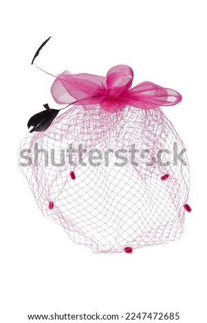 Close-up shot of a pink fascinator with a multi layered bow and a veil decorated with feathers. The fascinator with an alligator clip is isolated on a white background. Front view. Royalty-Free Stock Photo #2247472685