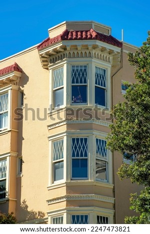 Moden spire or house tower with bay windows in midday sun with front yard trees and blue sky background with some shade. In the city or in the downtown neighborhoods of San Francisco California.