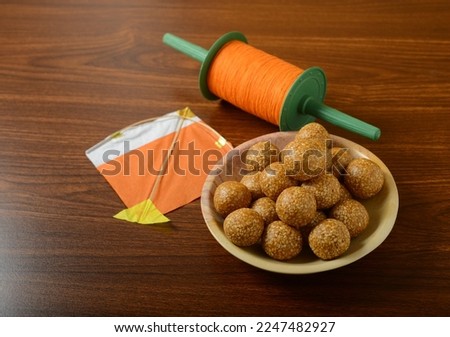 Bowl of Til or sesame laddoo placed along with kite and Manja Chakri. Makar Sankranti food, objects and background. Royalty-Free Stock Photo #2247482927