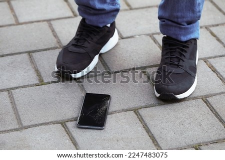 Man near dropped smartphone on pavement, closeup. Device repairing