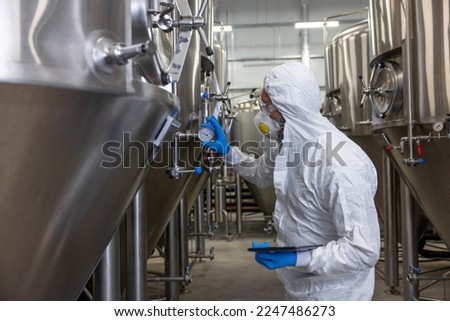 Beer tech checking the brewing equipment in the factory Royalty-Free Stock Photo #2247486273