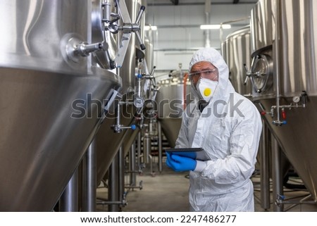 Experienced engineer overseeing the beer production equipment in a factory Royalty-Free Stock Photo #2247486277
