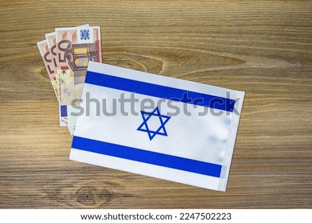 Coins and israeli flag placed on wooden background.