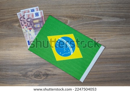 Coins and brazil flag placed on wooden background.