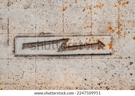 Lightning sign. Metal rusty arrow. Electricity sign on the sidewalk. Warning sign on the pavement