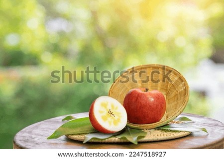 Fresh Red Honey core Apple in wooden basket, Golden Red Kotoku Apple in the basket over green natural Blur background.