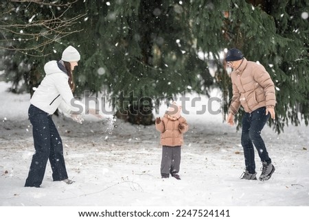 Family with little girl are having fun outdoor in winter. Enjoying spending time together. Family concept. High quality photo