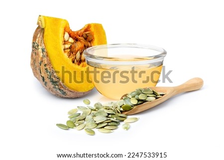 Pumpkin seed oil in glass bowl and dry pumpkin seed isolated on white background.