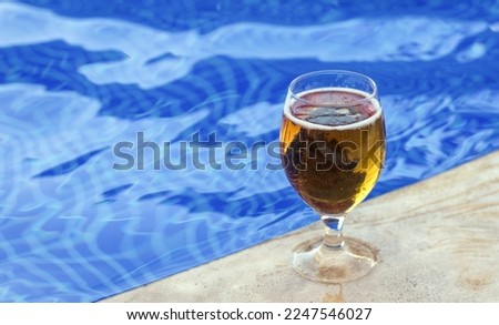 glass with fresh cold beer on pool edge blue color water waves mockup free space for text copy paste.vacation time mood travel all inclusive hotel trip relax on lounger sea beach 