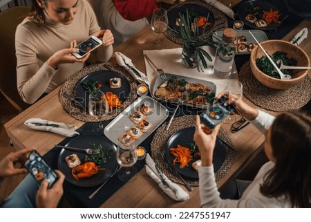 View from above of people taking pictures of their dinner plates using smart phones
