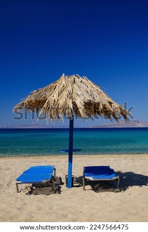 Two sun beds and a sun umbrella at the amazing beach of Agia Theodoti in Ios Greece