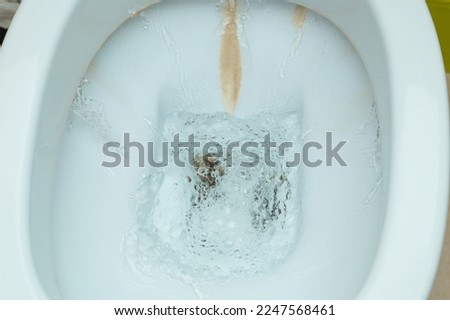 Dirty toilet bowl with limescale stain deposits. A toilet with traces of limescale, salt and stone deposits on the tiles Royalty-Free Stock Photo #2247568461
