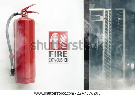 Fire Extinguisher on a white wall, with extinguisher sign in a room with smooke