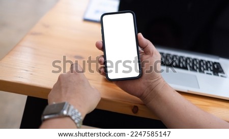 Mockup image of woman holding smartphone with blank white screen at home