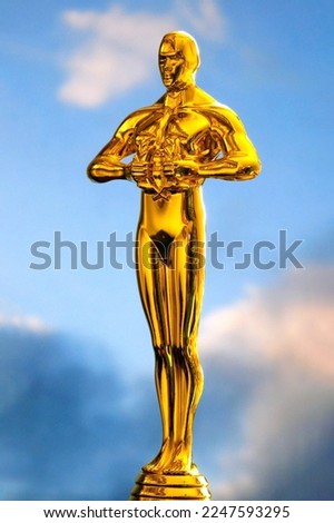 Hollywood Golden Oscar Academy award statue on blue background with light rays. Success and victory concept.