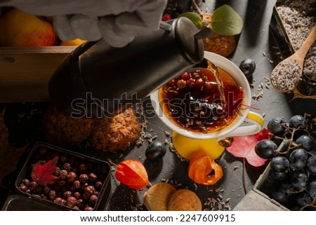 Dark food: herbal tea in a cup. Fruits and berries are on the table. Photo clip art