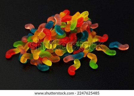 Heap of colorful gummy worms on black background.