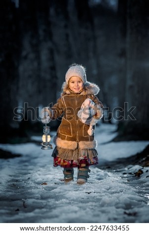 Little girl at night in the forest with a flashlight in winter