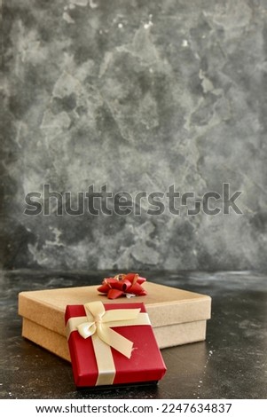  Gift box on a dark background, decorated with a textured bow and feathers, creating a romantic atmosphere for anniversary presents, valentine and birthday gift, post cards. Close up, copy space 