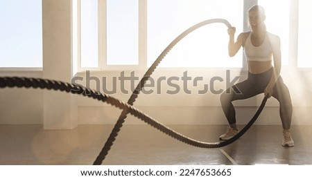 Young athletic woman with perfect body doing crossfit exercises with a rope in the gym. Royalty-Free Stock Photo #2247653665