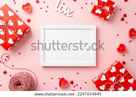 Valentine's Day concept. Top view photo of gift boxes photo frame heart shaped candles inscription love spool of twine and sprinkles on isolated pastel pink background with copyspace