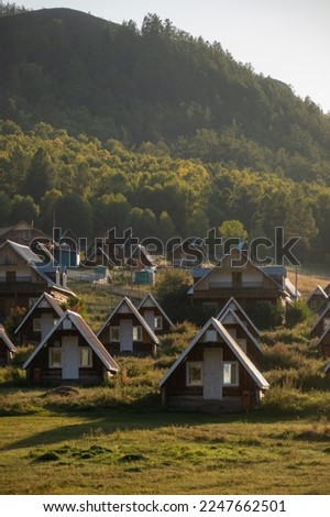 Cute small village houses on a foothill on a sunny day. Rural nomadic living, beautiful mountain in the background, golden hour.
