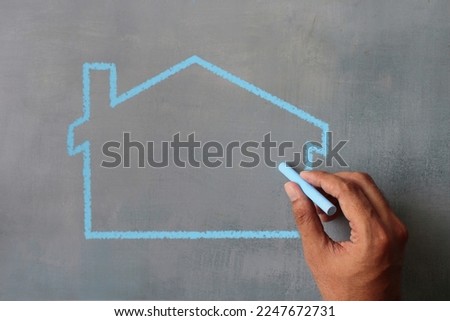 Top view image of hand drawing house icon on chalkboard. Copy space for text