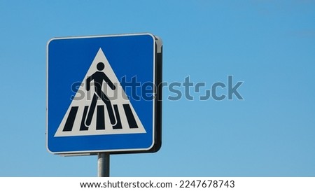 road sign pedestrian crossing close-up against the blue sky.