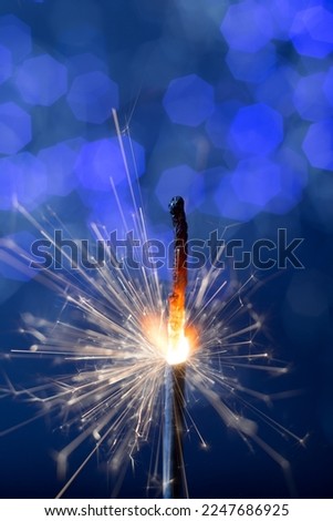 burning flickering sparkler new year fire on the background of blue lights bokeh