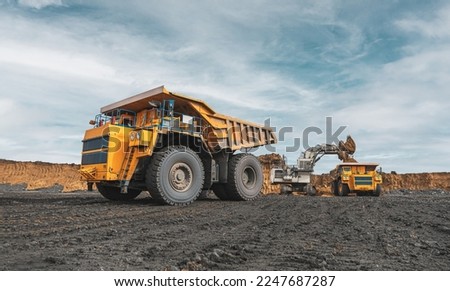 Large quarry dump truck. Big yellow mining truck at work site. Loading coal into body truck. Production useful minerals. Mining truck mining machinery to transport coal from open-pit production Royalty-Free Stock Photo #2247687287