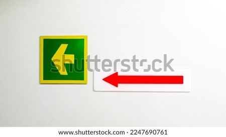 Green yellow left arrow acrylic sign with red arrow  on white acrylic sign on white background. 