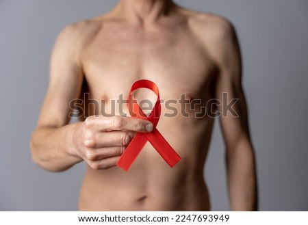 Still life. Studio shot of a folded red ribbon held by a shirtless man