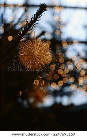 golden star decoration on the Christmas tree against the background of yellow lights
