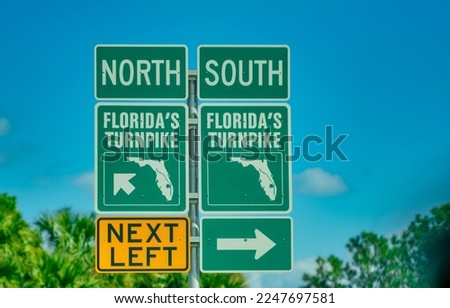Florida's turnpike road signage against palms and blue sky.
