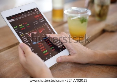 Woman hand using a tablet for Stock exchange trading online in the coffee shop, business concept