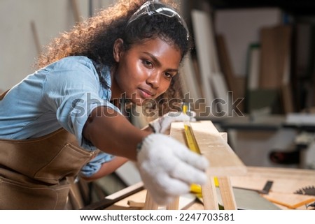 African American female carpenter working skillfully using tape measure pine raw materials to make handmade furniture chairs in the house. Royalty-Free Stock Photo #2247703581