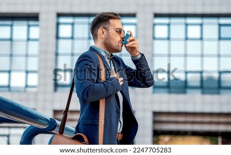 Stress and asthma. Young businessman treating asthma attack with inhaler. Health care concept Royalty-Free Stock Photo #2247705283