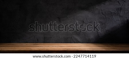 Wooden table or counter top with black stone wall background
